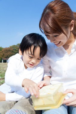 Neşeli Asyalı anne ve oğlu parkta piknik yapıyor.