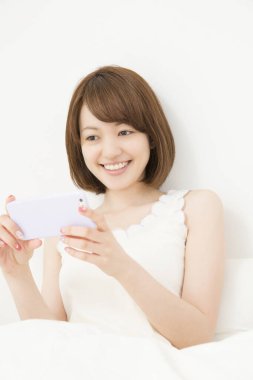 Gülümseyen güzel Japon kadın akıllı telefon kullanıyor.