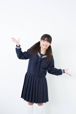 Genç, güzel Asyalı kız beyaz arka planda okul üniforması giyiyor..
