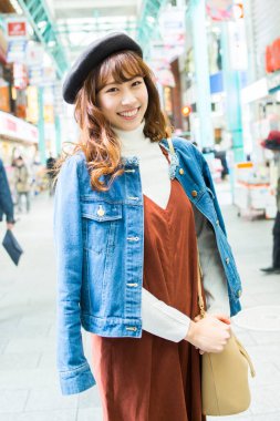 Alışveriş merkezinde dururken gülümseyen Asyalı kadın.