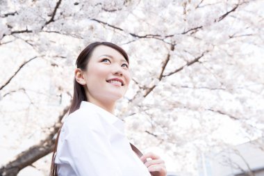 Genç, güzel Çinli kadın bahar parkında poz veriyor.