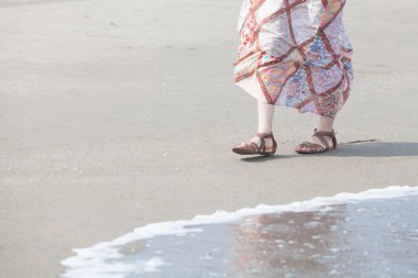 Kumsalda uzun etek giyen genç bir kadının alçak görünümü