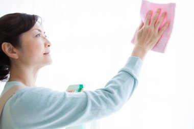 Camı bezle temizleyen Asyalı kadın.