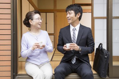 İş adamıyla çay içen Asyalı yaşlı kadının portresi.