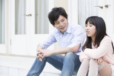 Asyalı baba ve genç kız evlerinde oturuyorlar. 