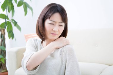 Evde omzunda ağrı olan bir kadın.