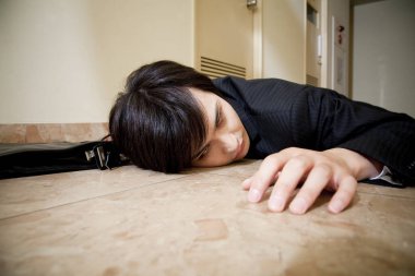 Takım elbiseli bir adam yerde yatıyor. 