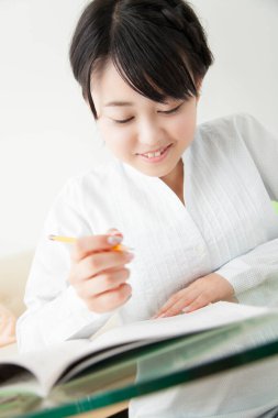 Güzel Asyalı kız evde ders çalışıyor.