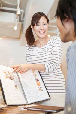 Kadın ve garson Asyalı kafede sipariş veriyor.