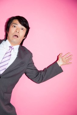 Pembe arka planda korkmuş genç Asyalı iş adamı