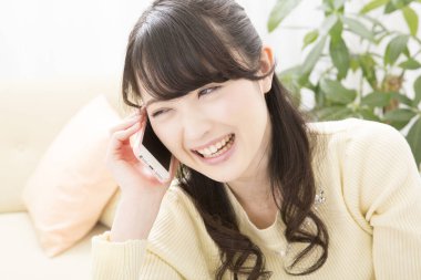 Akıllı telefondan konuşan gülümseyen Asyalı kadın, yakın plan portre 