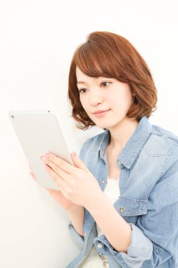 Dijital tablet kullanan gülümseyen Asyalı kadın