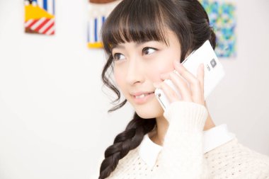 Güzel Asyalı genç bir kadın telefonda konuşuyor.