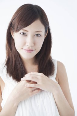 Stüdyoda poz veren beyaz bluzlu genç bir kadın.