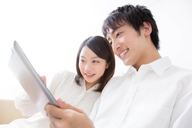 Bir adam ve bir kadın kanepede oturup tablete bakıyorlar.