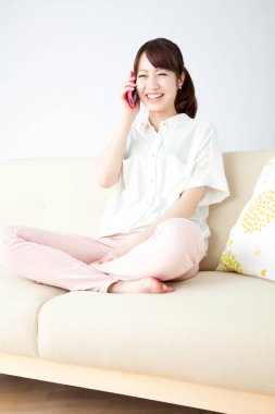 Kanepede akıllı telefondan konuşan genç bir kadın.