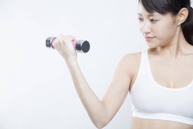 Gri stüdyo arka planında spor giysili güzel bir Asyalı kadının portresi.