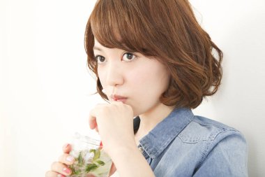 Güzel genç Japon kadının portresi ferahlatıcı bir içecek içiyor.