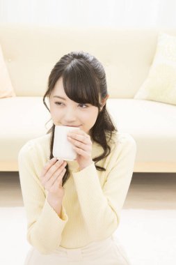 Güzel Asyalı kadın evde çay içiyor. 