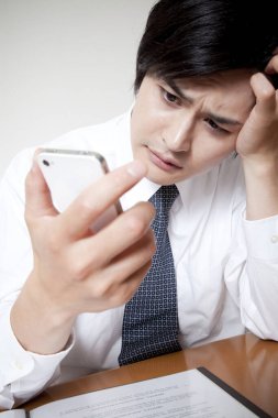 Başı ağrıyan akıllı telefon kullanan iş adamı