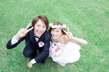 Genç Asyalı düğün çifti parkta poz veriyor.