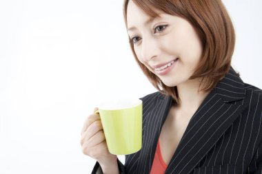 Beyaz arka planda bir kupa kahve tutan Asyalı kadın. 