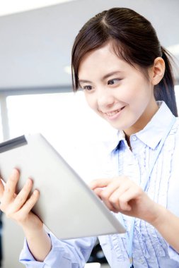 Ofisinde tablet bilgisayarı olan genç bir kadın. 