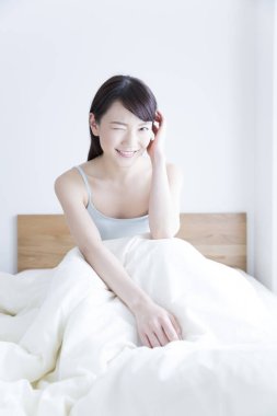 Genç kadın yatakta göz kırpıyor.