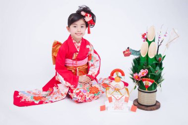 Beyaz stüdyo arka planında geleneksel kırmızı kimono giyen güzel Japon kızın portresi.