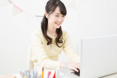 Asyalı iş kadını evde dizüstü bilgisayar kullanıyor. 