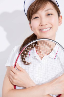 Beyaz stüdyo arka planında tenis oynayan Asyalı kadın