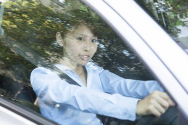 Genç mutlu Asyalı kadın araba kullanıyor.