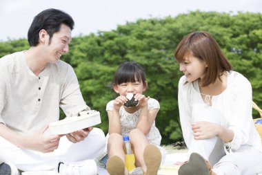 Sevgili Asyalı aile, anne, baba ve kız parkta piknik yapıyorlar.