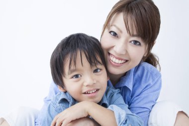 Stüdyoda poz veren Asyalı genç anne ve tatlı oğlunun portresi.