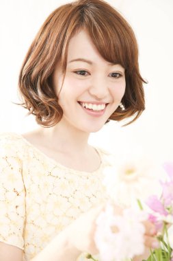 Çiçeklerle gülümseyen güzel Asyalı kadın