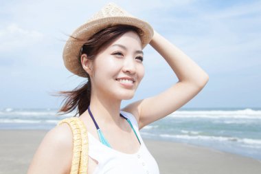 Kumsalda çanta taşıyan genç Asyalı kadın.