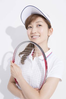 Beyaz stüdyo arka planında tenis oynayan Asyalı kadın