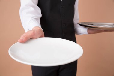 Boş tabağı olan genç bir garson. 