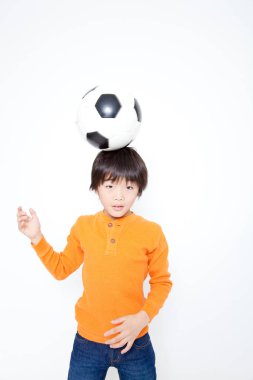 Beyaz arka planda izole edilmiş Asyalı çocuk futbol oynuyor.