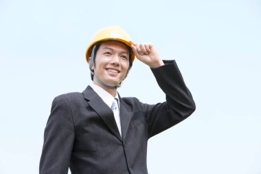 Gökyüzünün arka planında genç Asyalı mimari miğferin portresi.