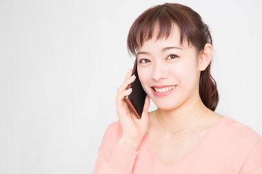 Beyaz arka planda akıllı telefondan konuşan Asyalı genç kadının portresi 