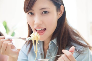 Genç Asyalı kadın erişte yiyor.