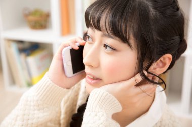 Güzel Asyalı genç bir kadın telefonda konuşuyor.