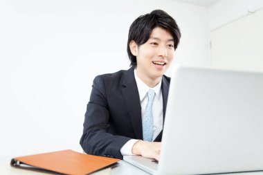 Genç Asyalı iş adamı laptopuyla ofiste. 