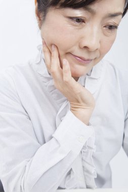 Asyalı olgun kadın beyaz arka planda düşünüyor 