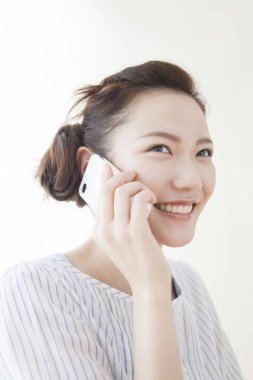 Beyaz arka planda izole edilmiş bir cep telefonu kullanan Asyalı kadın. 