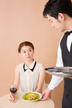 Beyaz elbiseli Asyalı kadın salata yiyor.