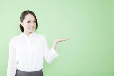 Asyalı kadın avuç içi ile bir şey gösteriyor.