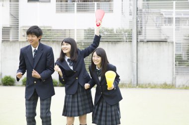 Aynı üniformayı giyen bir grup öğrenci okullarında birlikte dikiliyorlar.