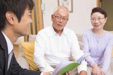 Gülümseyen çift danışmanla belgeleri tartışıyor.